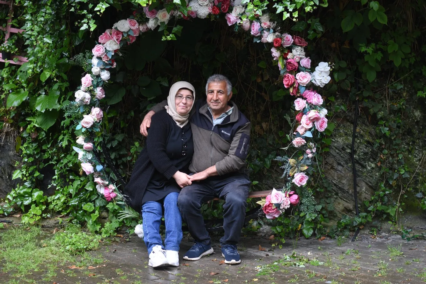 Çiçeklerden bir çemberin içinde oturan annemle babam