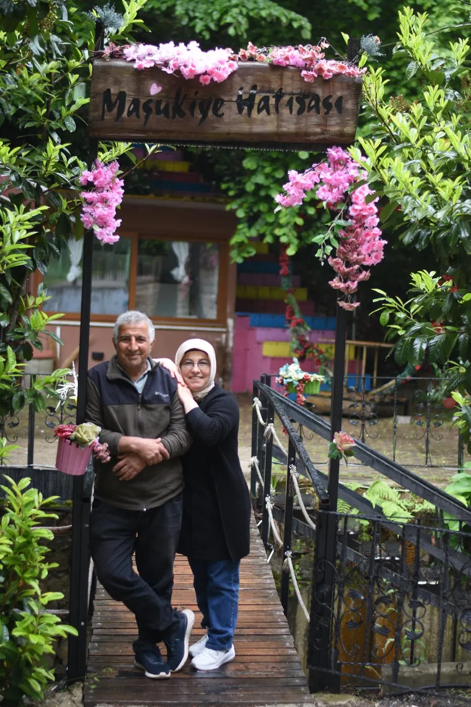 Çiçeklerle süslü “Maşukiye Hatırası” kemerinin altında annemle babam