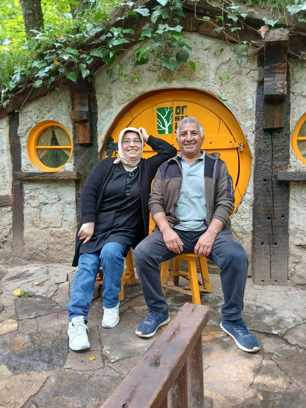 Yuvarlak sarı kapılı taş evin önünde oturan annemle babam