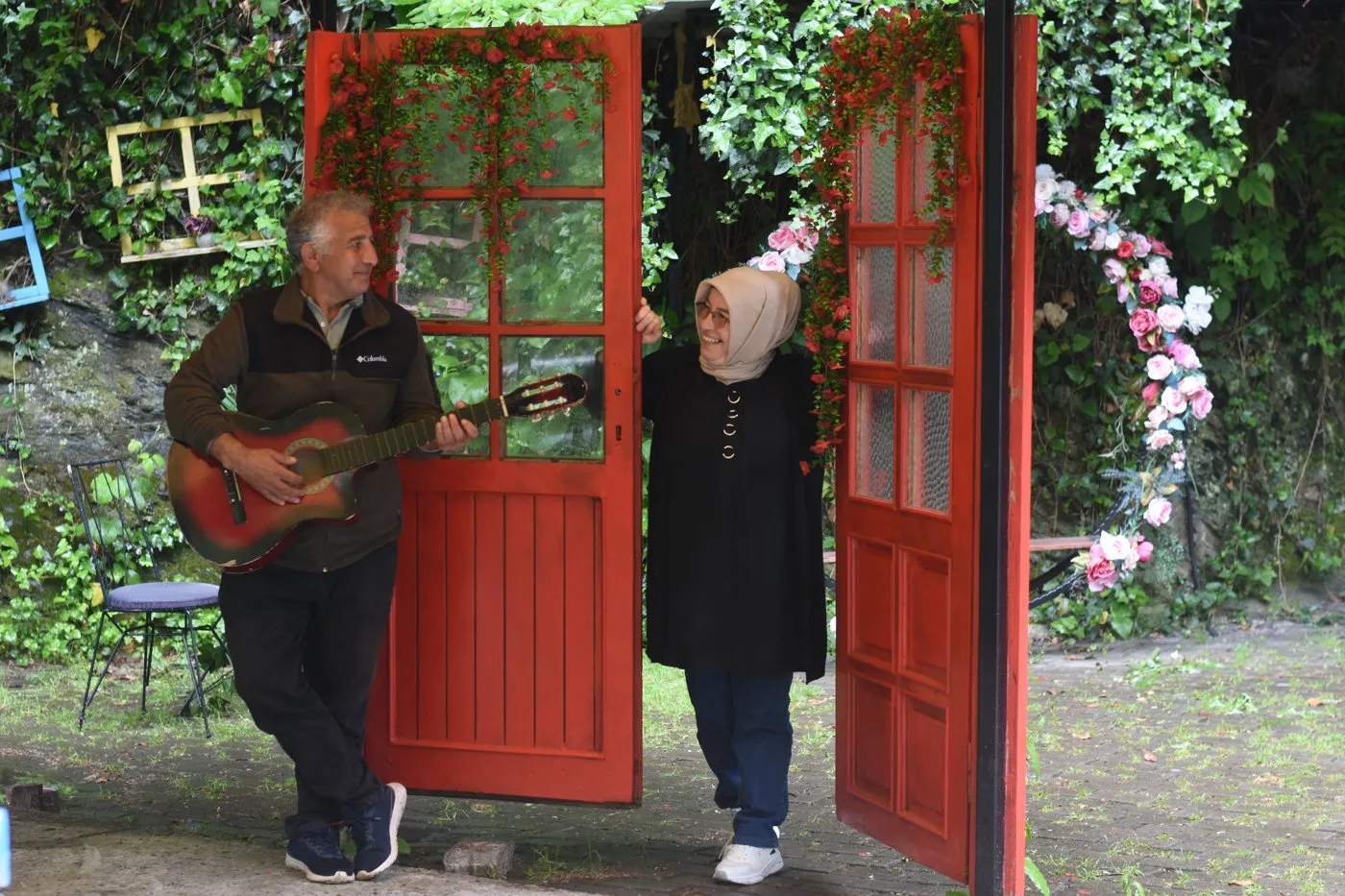Kırmızı bir kapının önünde, elinde gitarla babam ve yanında annem