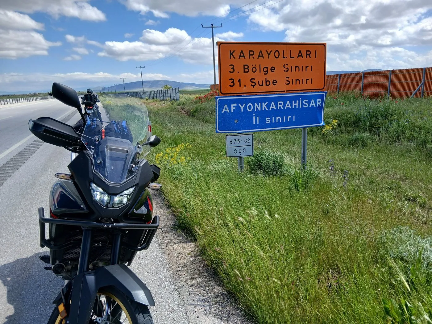 Afyonkarahisar il sınırı tabelasının yanında duran motosiklet