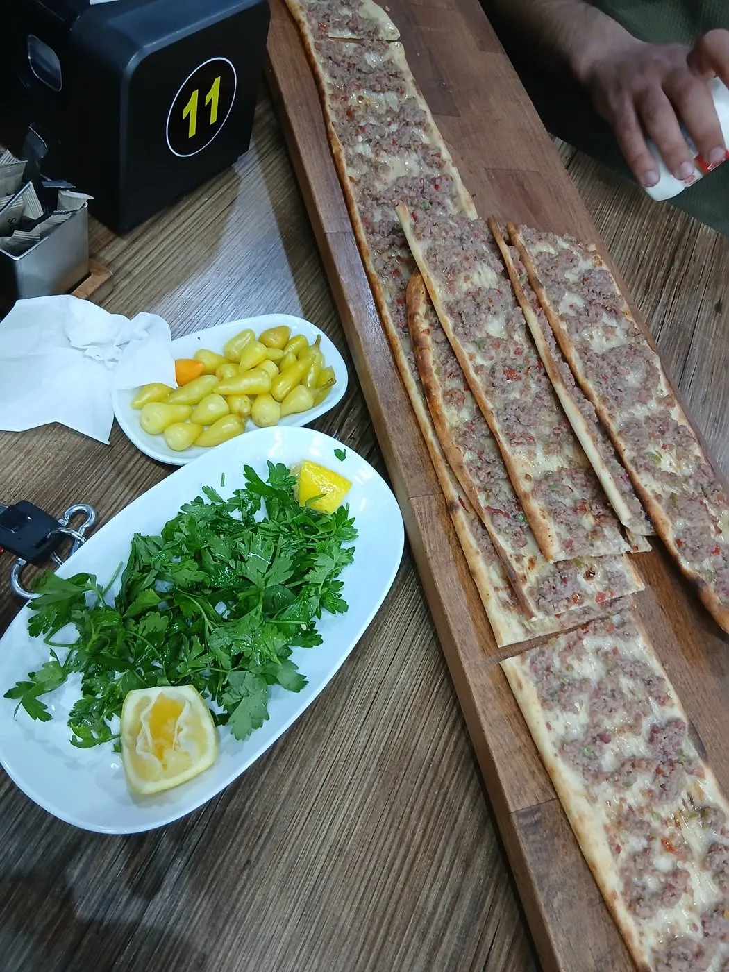 Tahta tabakta dilimlenmiş Konya etli ekmeği, yanında roka ve limon