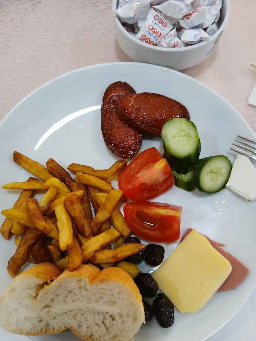 Konukevindeki kahvaltı tabağı: sucuk, patates, domates, salatalık, peynir
