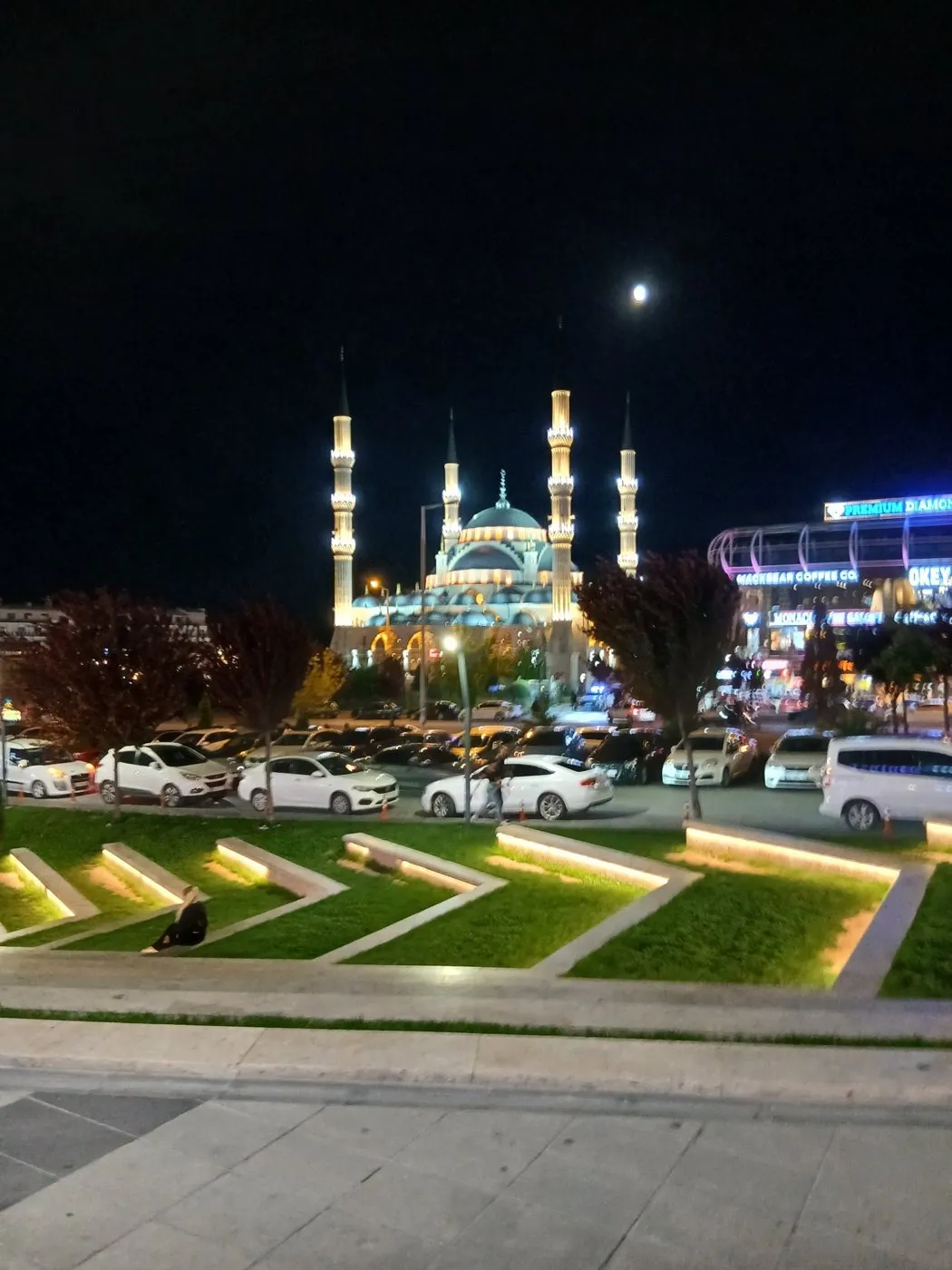 Gece ışıklandırılmış bir cami ve önündeki meydan