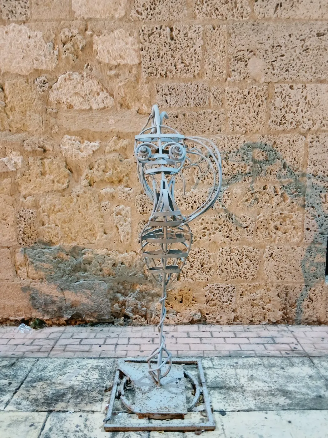 Taş duvarın önünde tel ve metalden yapılmış soyut bir figür